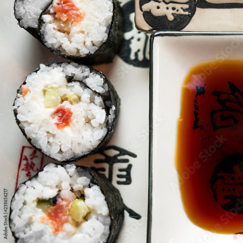 Chumaki Sushi Rolls with Tuna, Salmon, Rice, Cucumber, Avocado And Nori Seaweed on a Plate with Soy Sauce Dipping Dish and Traditional Chinese Calligraphy. Flat Lay Top-Down Composition. photo