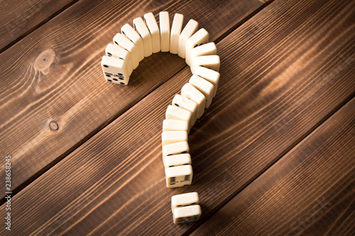 Domino question mark on wooden table. Domino principle photo