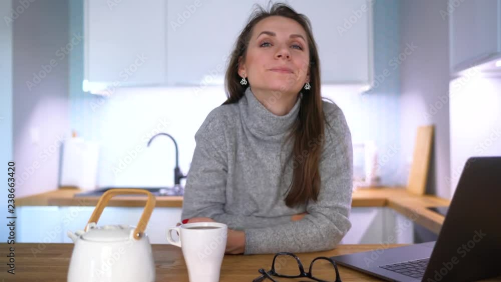 Portrait of caucasian woman who has breakfast in the kitchen and using a laptop Portrait of caucasian woman who has breakfast in the kitchen and using a laptop