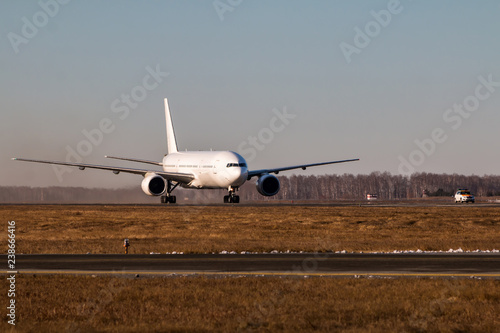 White wide body passenger airplane moves behind the Follow-me-Car on the main taxiway