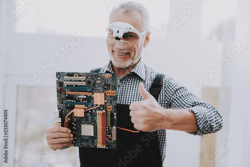 Standing Old Worker with Motherboard in Hand. photo