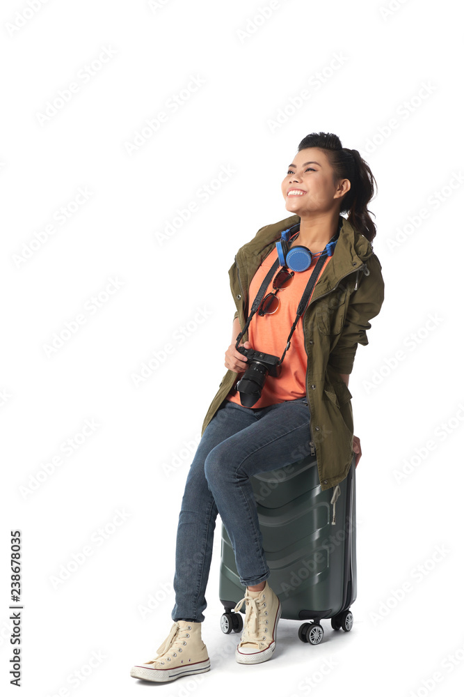 Excited happy Vietnamese young woman sitting on suitcase, isolated on white Excited happy Vietnamese young woman sitting on suitcase, isolated on white