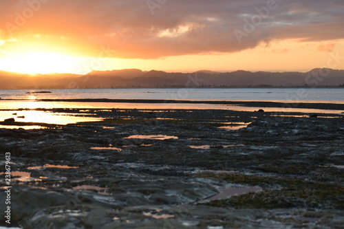 The beach rock pools reflect the sunset sky in Gisborne  New Zealand.
