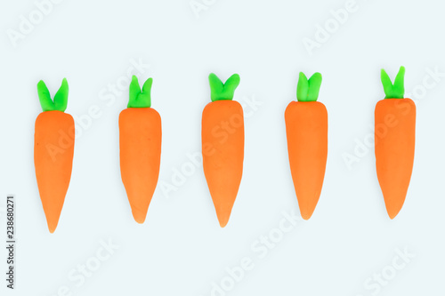 Raw of cute orange carrot vegetable with green leaves made from Plasticine clay Isolated on white background.
