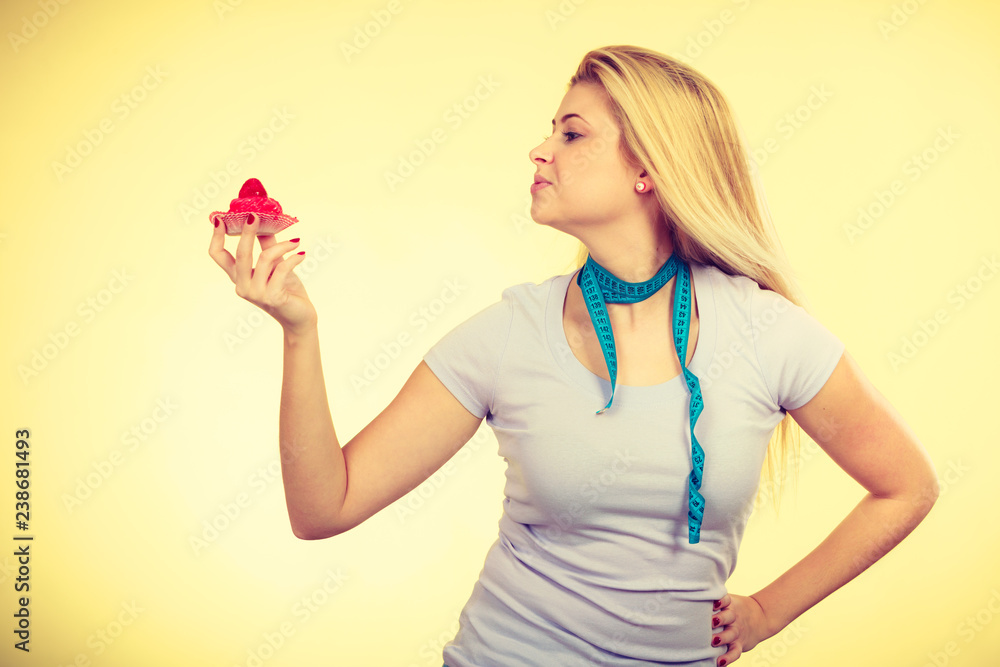 Woman holding cupcake, measure tape on neck Woman holding cupcake, measure tape on neck