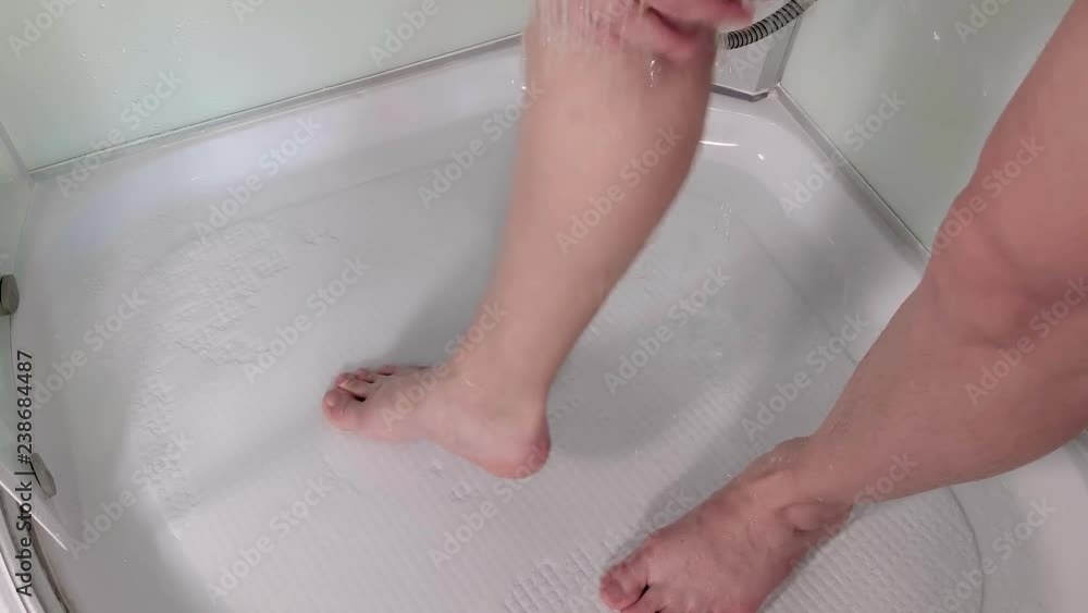 Sexy young woman shaving her leg with foam in shower cabin. Close-up view of female leg. Girl hand depilating her leg at bathroom. Sexy young woman shaving her leg with foam in shower cabin. Close-up view of female leg. Girl hand depilating her leg at bathroom.