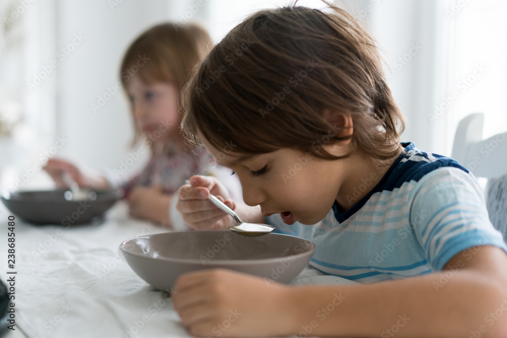 Kids in dining room eating and watching tablet Kids in dining room eating and watching tablet