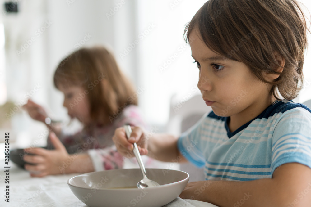 Kids in dining room eating and watching tablet Kids in dining room eating and watching tablet