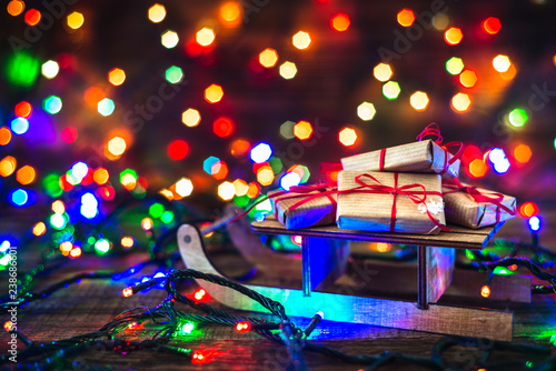 Christmas gifts on light background. Blur lights and magic atmosphere under tree with gift boxes on santa sleigh.