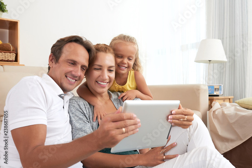 Happy family of three watching movie on tablet computer together