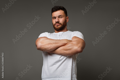 Suspicious young man with crossed big muscular arms photo
