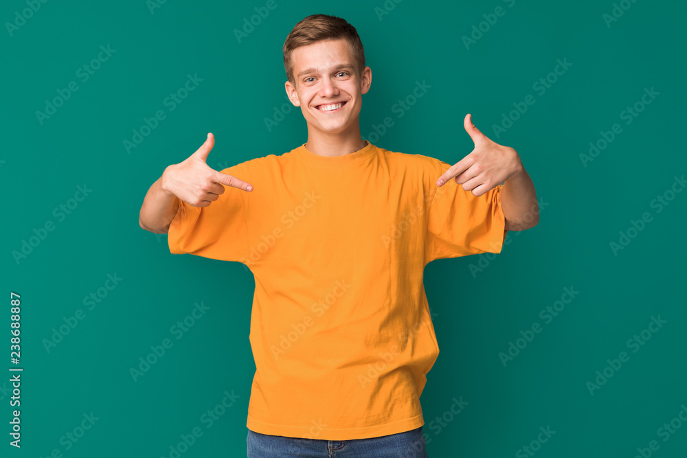 Teen guy pointing at copy space on his t-shirt