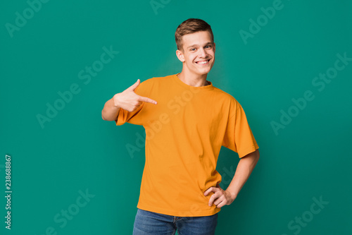 Teenager pointing at copy space on his t-shirt