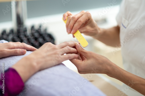 Manicurist shaping the nails with a file
