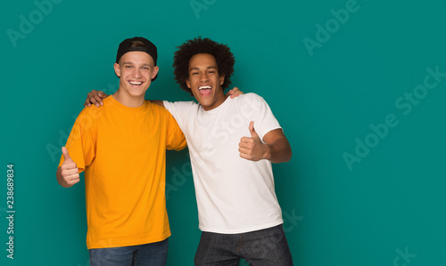 Teenage friends showing thumbs up over blue background photo