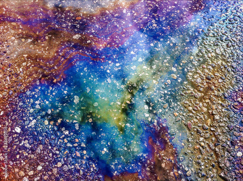 Rainbow colors from spilled oil on wet asphalt.