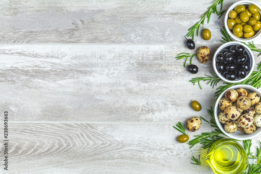 Black and green olives, quail eggs on plates, olive oil and rosemary Black and green olives, quail eggs on plates, olive oil and rosemary