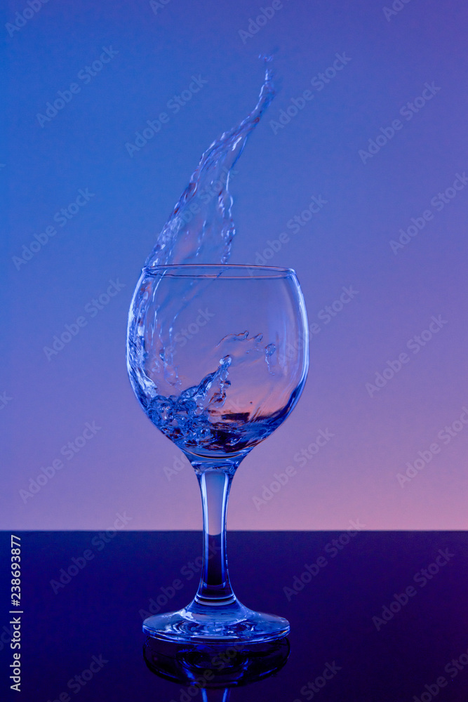 Splash of wine in a glass. Drink in glass on a blue background. Splash of wine in a glass. Drink in glass on a blue background.