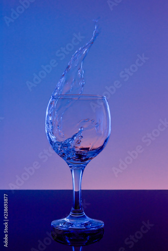 Splash of wine in a glass. Drink in glass on a blue background.