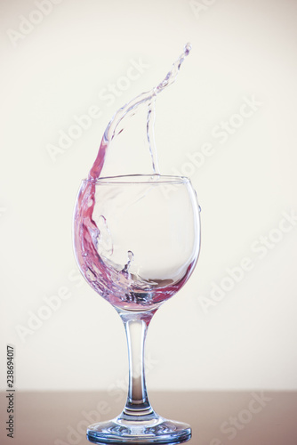 Splash of wine in a glass. Pink drink in glass on a white background.