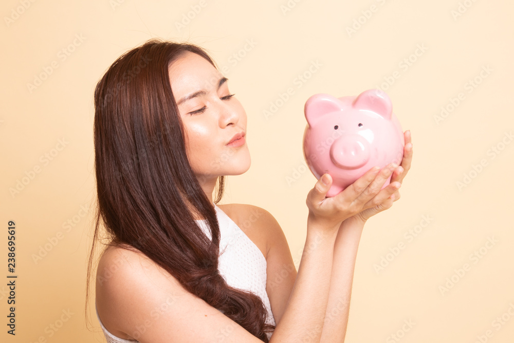 Young Asian woman kiss a pink coin bank. Young Asian woman kiss a pink coin bank.