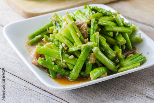 stir-fried asparagus in plate on wooden table.