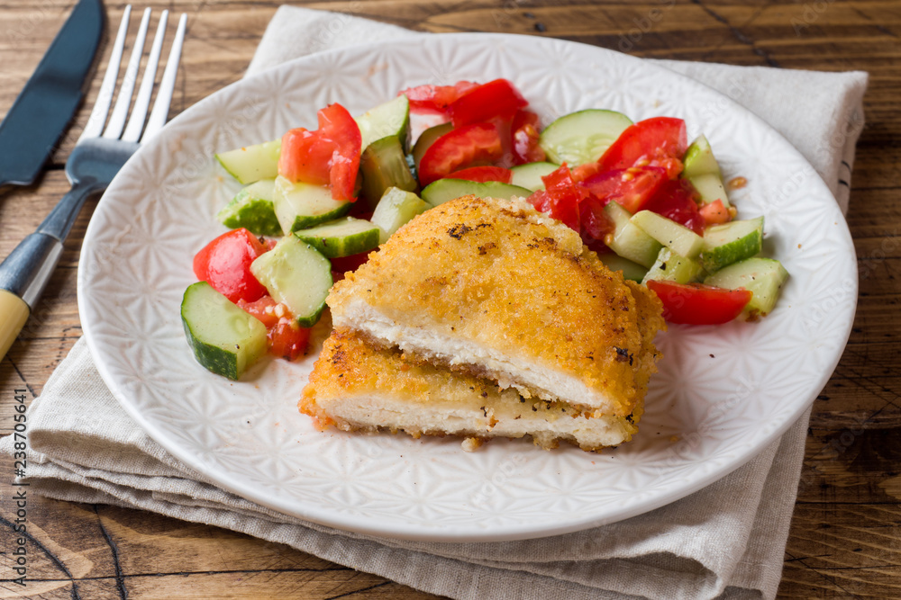 Chicken cutlet and cucumber salad with tomatoes on a wooden table