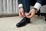 The bridegroom is dressed for a wedding ceremony. Hands and shoes close-up.