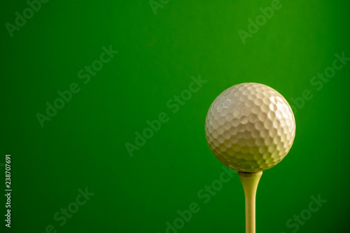 Close-up of a golf ball on a tee. Green background. Copy space.