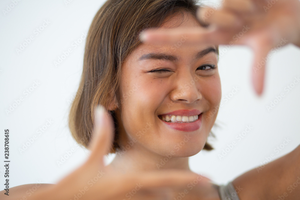Smiling Asian woman looking at camera and making frame gesture. Pretty young girl posing and winking. Portrait concept. Isolated front view on white background. Smiling Asian woman looking at camera and making frame gesture. Pretty young girl posing and winking. Portrait concept. Isolated front view on white background.