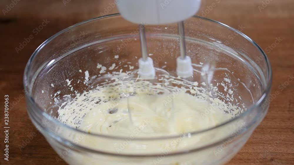 Whipping cream with electric mixer. Add yolk while mixing cream in glass bowl. Home bakery. Whipping cream with electric mixer. Add yolk while mixing cream in glass bowl. Home bakery.