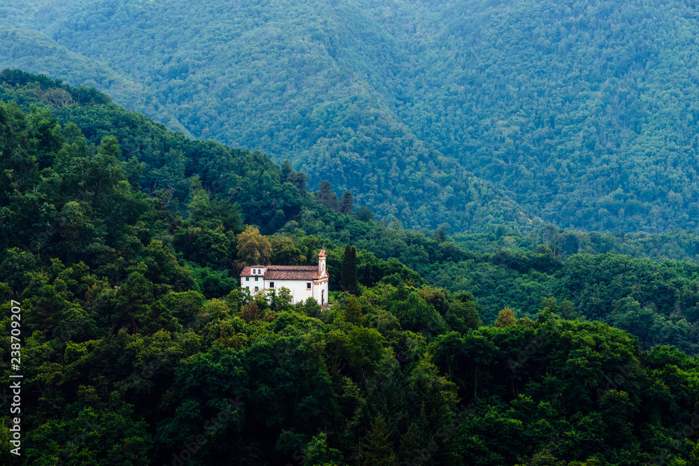 Catholic church outstanding alone in the forest green hills of Toscany, Italy