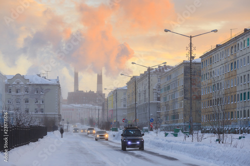 Northern industrial city. Sunset. Smoke from the chimney is visible above the houses. Bogdan Khmelnitsky Street. Norilsk, Krasnoyarsk region, Siberia, Russia. photo