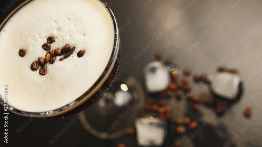 Glass with coffee drink, white crema, coffee beans, black background, ice cubes. Close up. Top view Glass with coffee drink, white crema, coffee beans, black background, ice cubes. Close up. Top view
