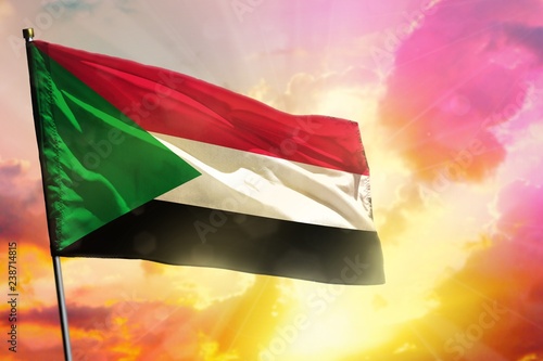 Fluttering Sudan flag on beautiful colorful sunset or sunrise background. Success concept.