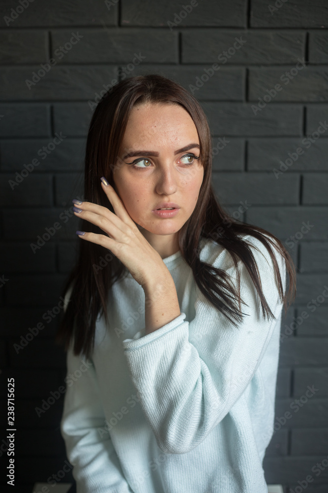 The closeup portrait of a young beautiful lady with dark hair on the dark gray background The closeup portrait of a young beautiful lady with dark hair on the dark gray background