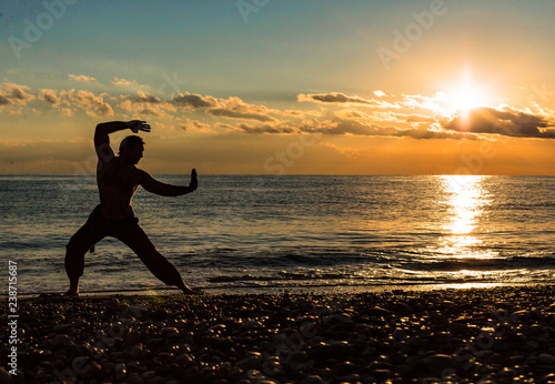 Silhouette of a man practises wing chun on the beach. photo