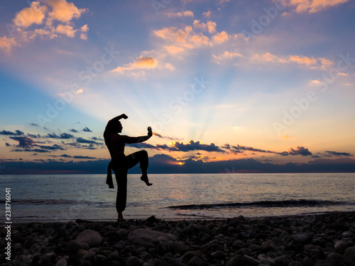 Silhouette of a man practises wing chun on the beach. photo