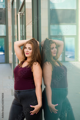 Pretty young woman walking on the city street. Casual fashion, plus size model. xxl women on nature.