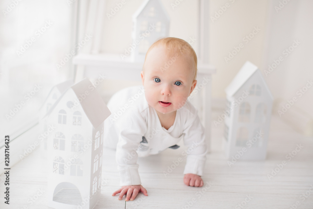 Baby crawling and smile on white floor near white paper decor houses Baby crawling and smile on white floor near white paper decor houses