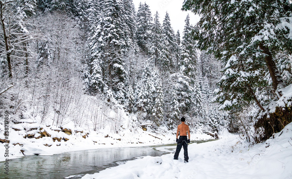 naked tempered man near a frozen river in winter forest in the mountains