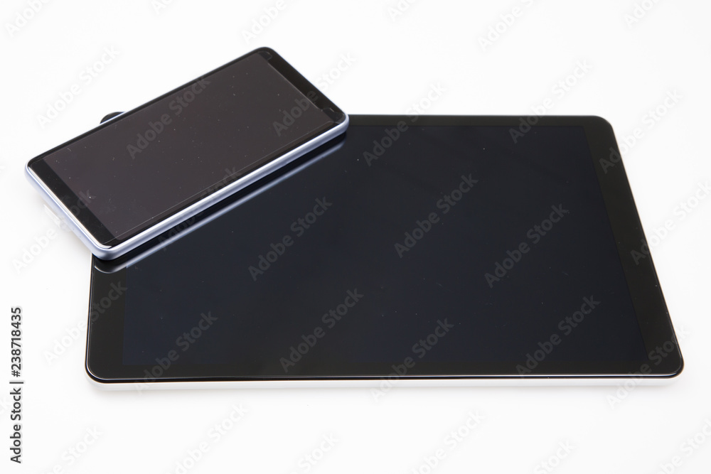 phone lying above tablet with touch screen isolated on white background phone lying above tablet with touch screen isolated on white background