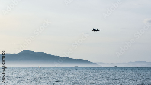 the plane against the backdrop of a clean blue sky flies on the sea and majestic mountains