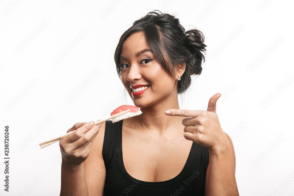 Cheerful young asian woman eating sushi with chopsticks Cheerful young asian woman eating sushi with chopsticks