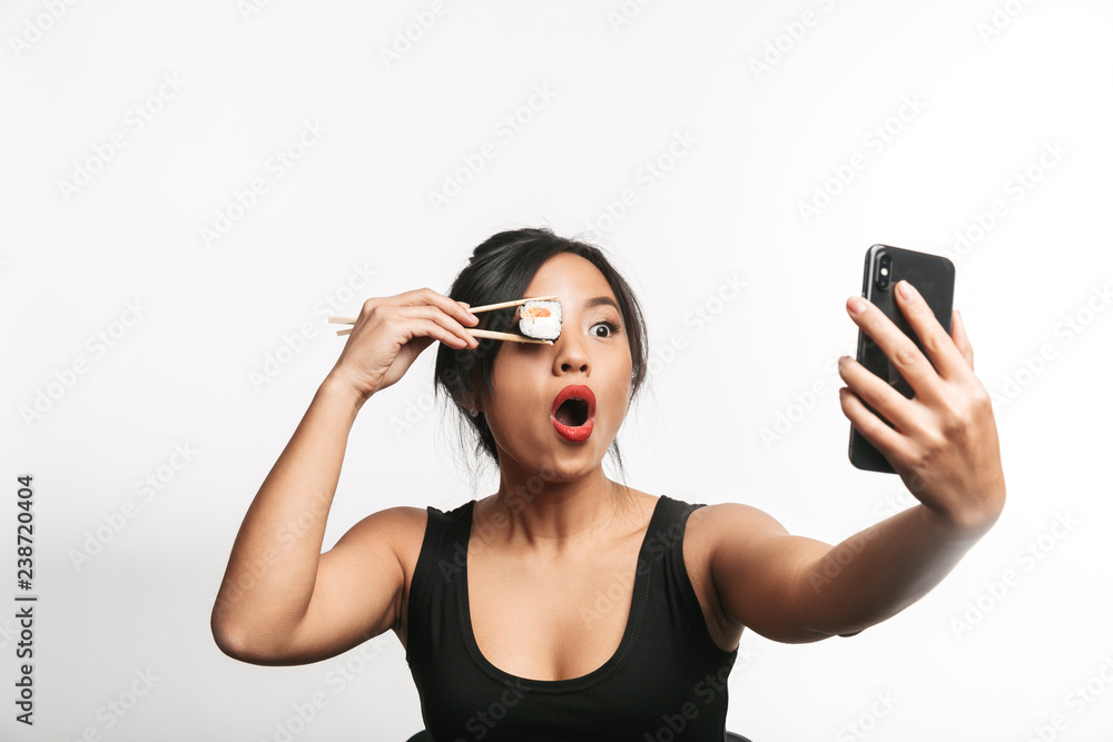 Cheerful young asian woman eating sushi Cheerful young asian woman eating sushi