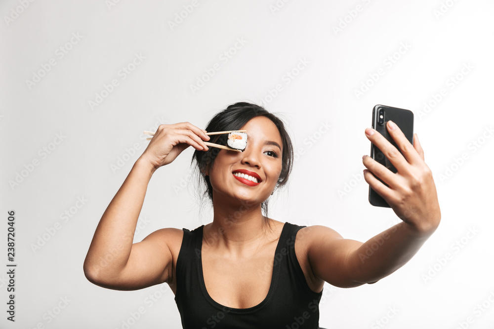 Cheerful young asian woman eating sushi Cheerful young asian woman eating sushi