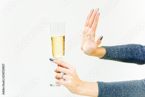 Hand of woman refusing glass with alcoholic beverage, on white background. No alcohol concept