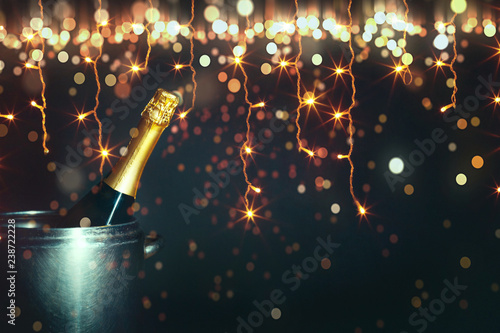 New Year 2019 Celebration Concept. Bottle of champagne on a background of holiday lights with copy-space