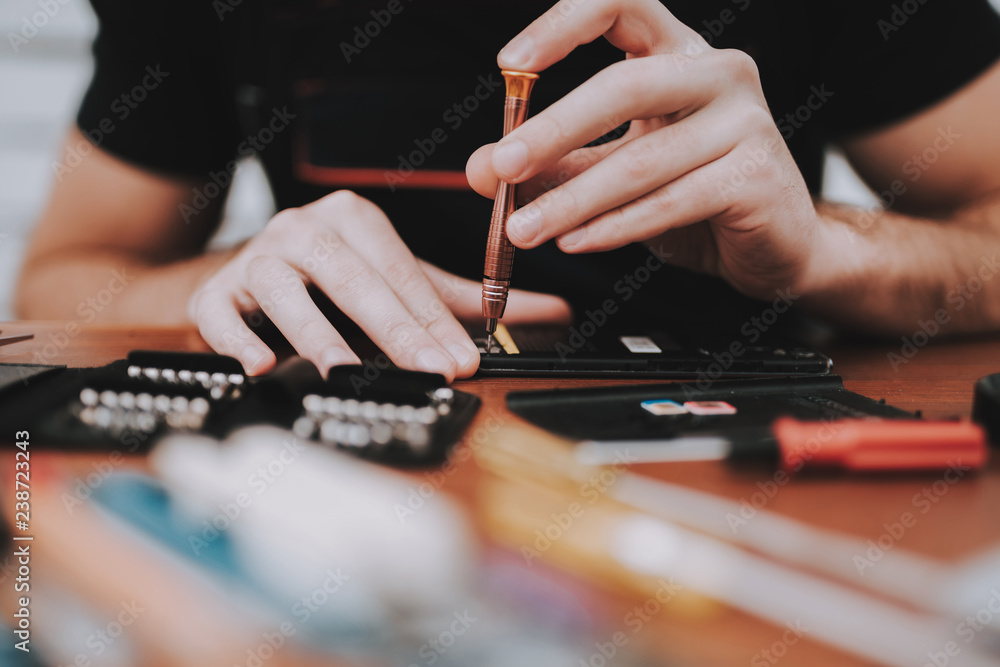 Fototapeta premium Close up Young Man Repairing Mobile Phone at Table