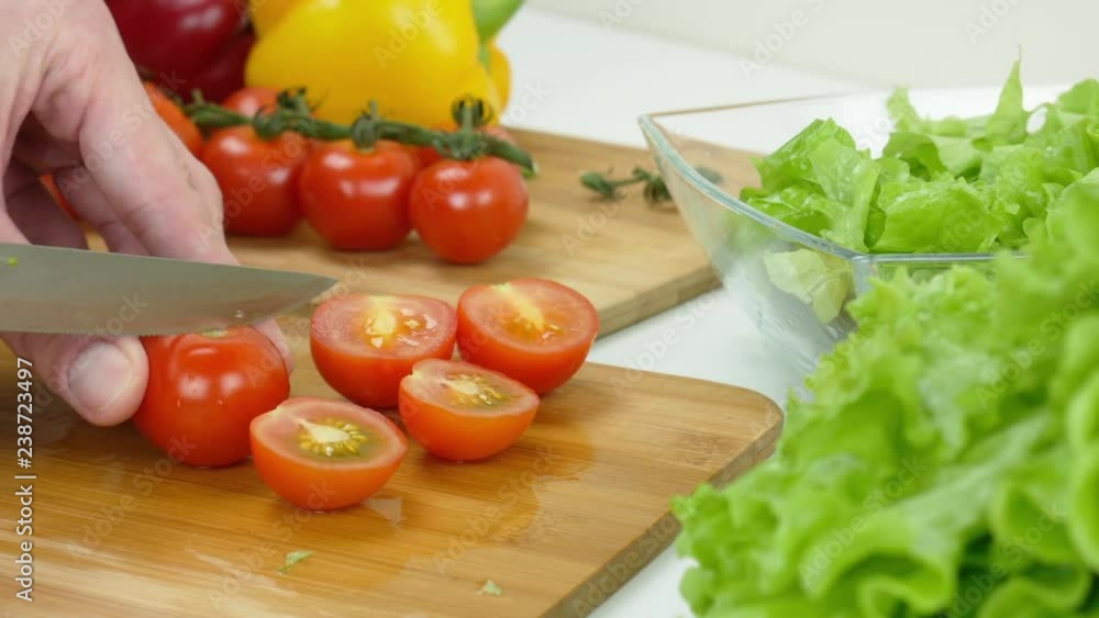 Healthy food. Vegetarian food. A man cuts a fresh tomatoes for salad Healthy food. Vegetarian food. A man cuts a fresh tomatoes for salad